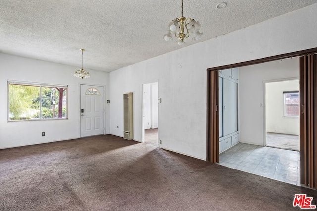 entrance foyer with a chandelier, carpet, and a textured ceiling