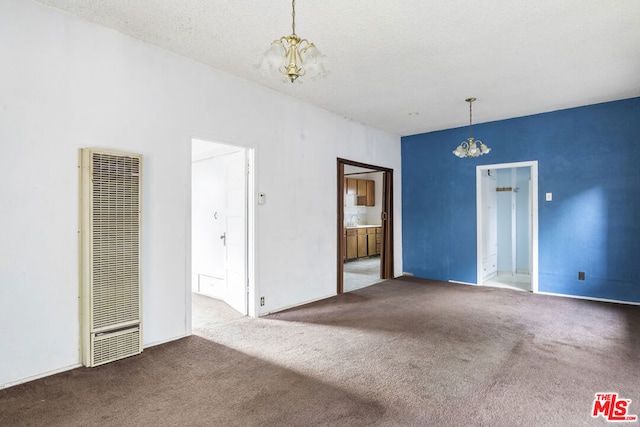 carpeted empty room with sink, a textured ceiling, and a chandelier