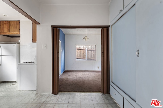 kitchen with pendant lighting, white appliances, washer / clothes dryer, and light carpet