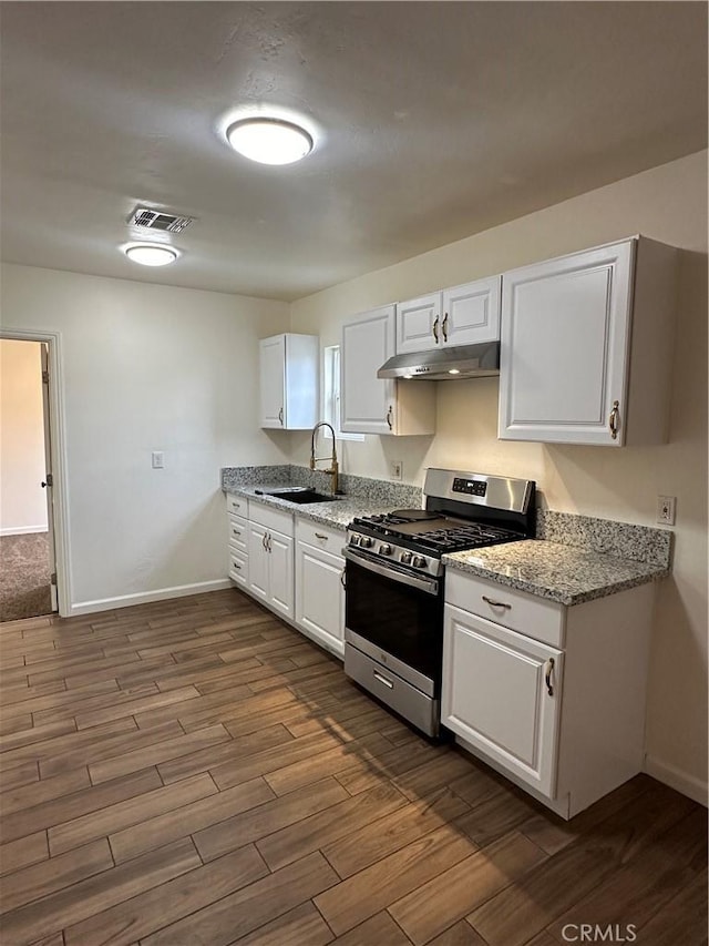 kitchen with sink, dark hardwood / wood-style floors, light stone counters, white cabinets, and stainless steel range with gas cooktop