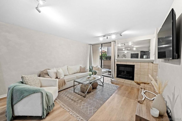 living room with hardwood / wood-style floors, a tile fireplace, and rail lighting