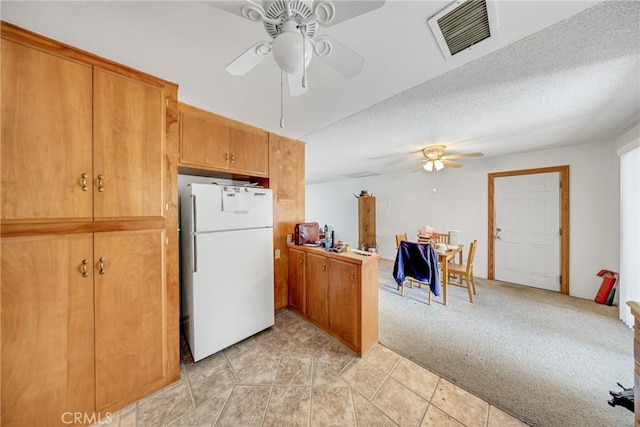 kitchen with white refrigerator, ceiling fan, light carpet, and a textured ceiling