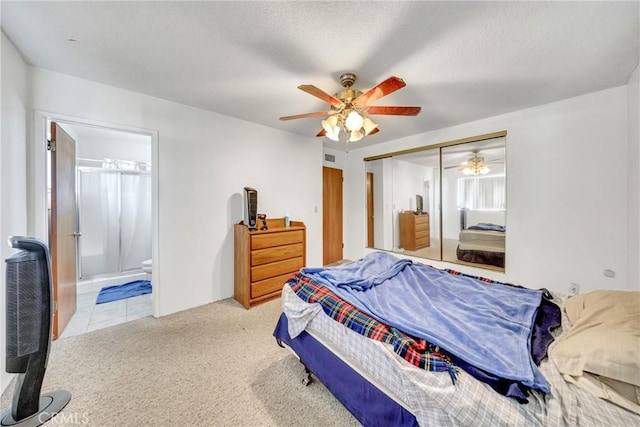 carpeted bedroom with ensuite bath, a closet, and ceiling fan