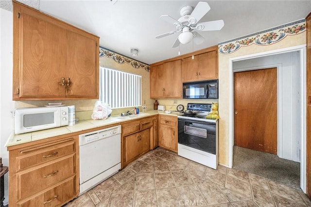 kitchen featuring sink, white appliances, light tile patterned floors, ceiling fan, and tile countertops