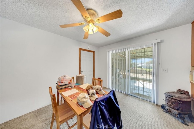dining space featuring ceiling fan, carpet flooring, a textured ceiling, and a wood stove