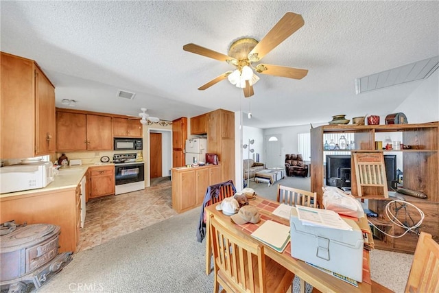 interior space featuring light countertops, visible vents, a ceiling fan, white appliances, and a textured ceiling