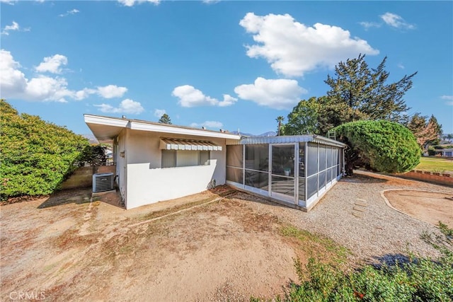 rear view of house featuring central AC unit and a sunroom