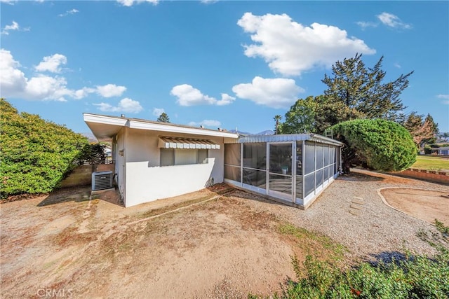 back of property featuring a sunroom, central AC, and stucco siding