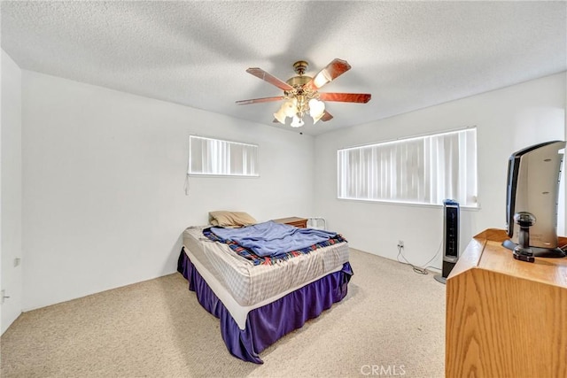 bedroom with ceiling fan, carpet, and a textured ceiling