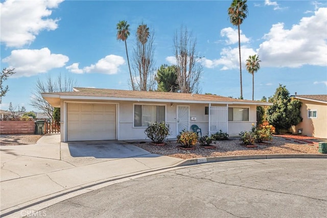 ranch-style home with stucco siding, an attached garage, and driveway
