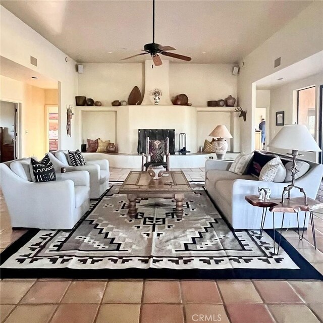 living room with a large fireplace and ceiling fan