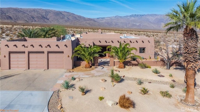 view of front facade featuring concrete driveway, a mountain view, an attached garage, and stucco siding