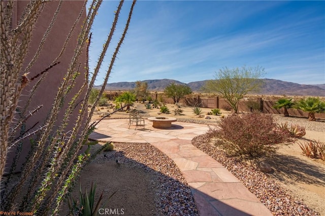 exterior space with a mountain view, a fire pit, and fence