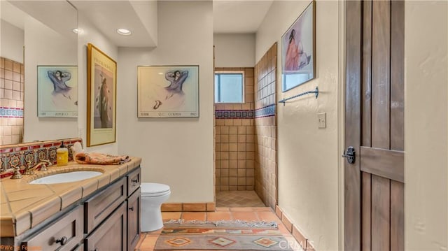 bathroom featuring a walk in shower, vanity, toilet, and tile patterned floors