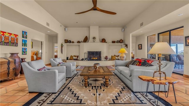 living area featuring light tile patterned floors, ceiling fan, visible vents, and a large fireplace