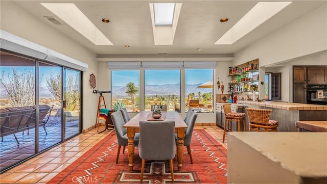 dining room featuring a bar, light tile patterned floors, visible vents, and a mountain view