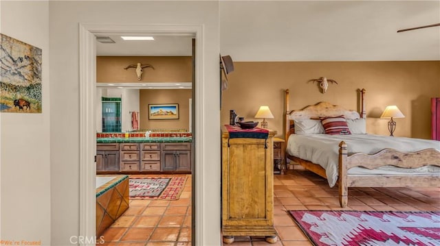 bedroom with ensuite bathroom and tile patterned floors