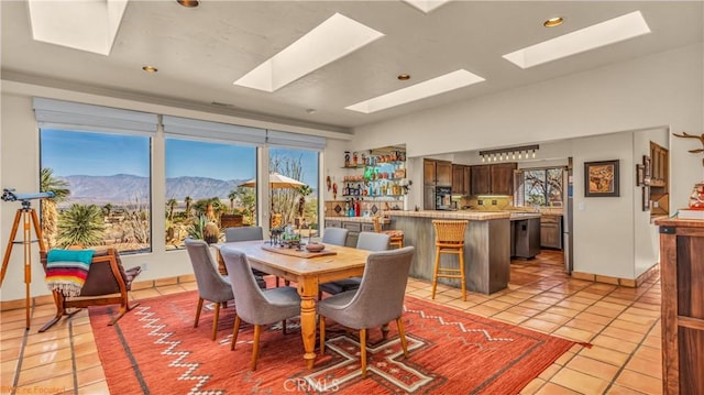 dining area with lofted ceiling, light tile patterned floors, a mountain view, and recessed lighting