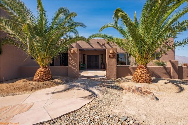 pueblo-style house featuring fence and stucco siding