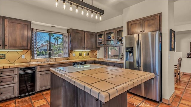 kitchen with glass insert cabinets, a kitchen island, tile countertops, and stainless steel fridge with ice dispenser