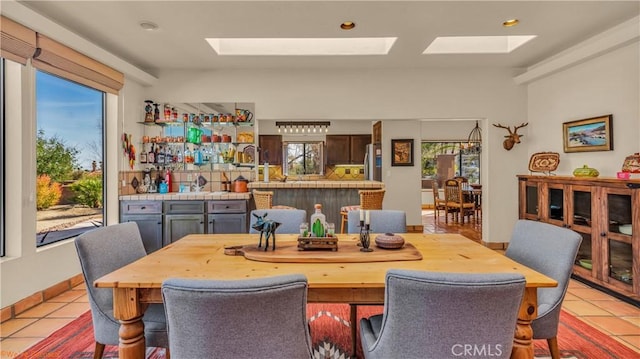 dining room featuring a skylight, baseboards, and light tile patterned floors