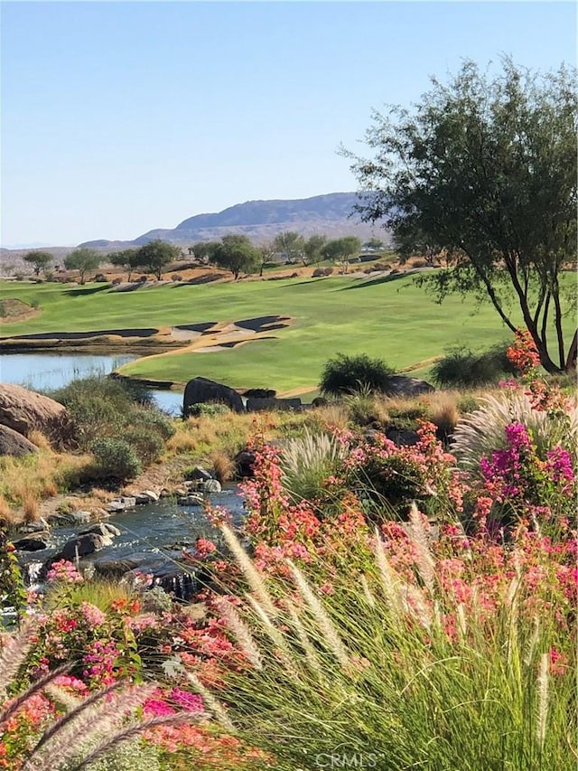 surrounding community with a yard, golf course view, and a water and mountain view