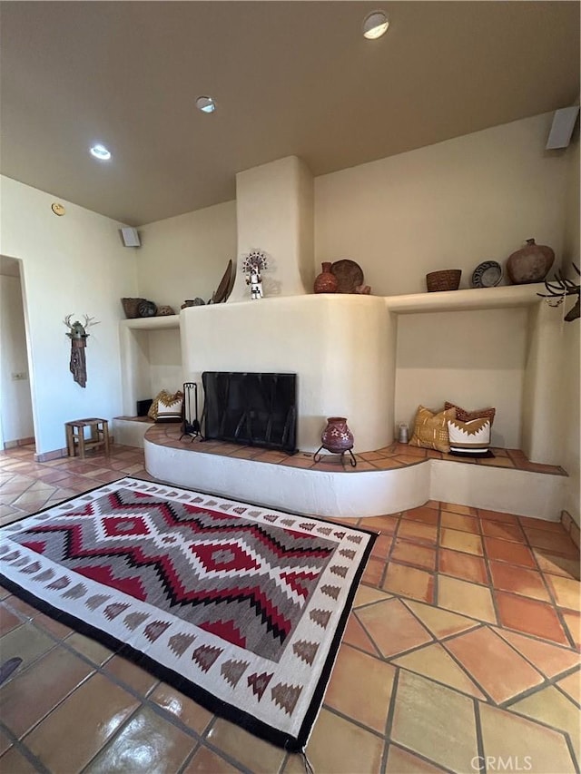 living area with tile patterned flooring, a fireplace with raised hearth, and recessed lighting