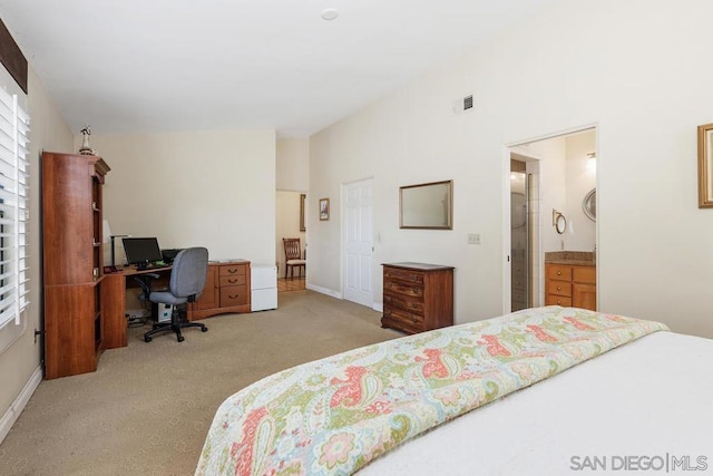 bedroom with vaulted ceiling, light colored carpet, and ensuite bath