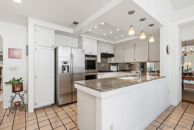 kitchen featuring sink, white cabinetry, dark stone countertops, stainless steel appliances, and kitchen peninsula