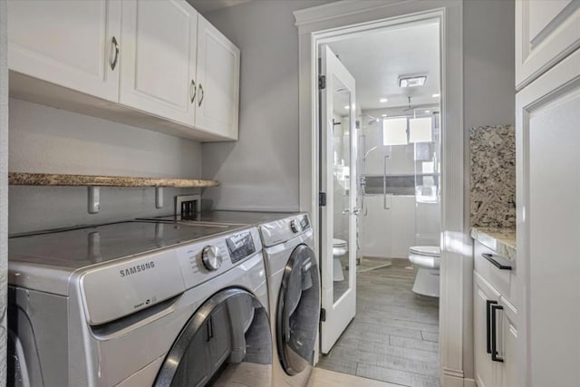 laundry room with cabinets, light wood-type flooring, and independent washer and dryer