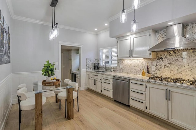 kitchen with white cabinetry, decorative light fixtures, light wood-type flooring, stainless steel appliances, and wall chimney range hood