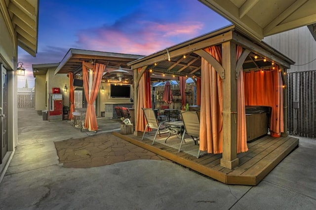 patio terrace at dusk with a hot tub and a gazebo