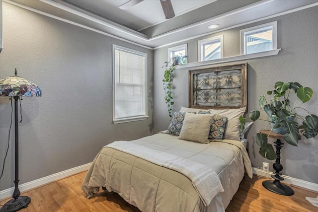 bedroom with a tray ceiling, hardwood / wood-style flooring, and ceiling fan