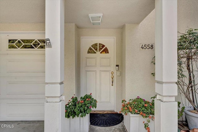 property entrance with a garage and stucco siding