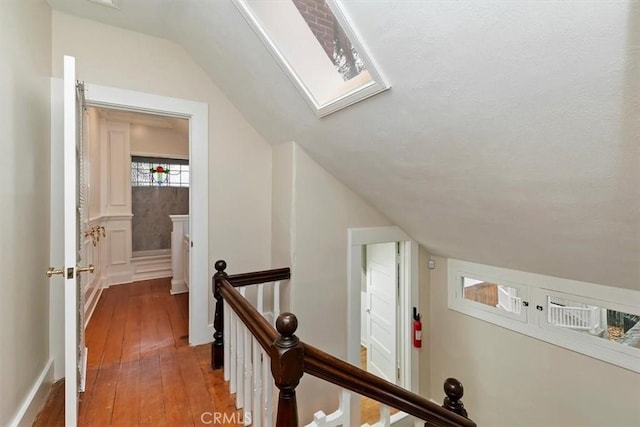 hallway featuring lofted ceiling with skylight and hardwood / wood-style floors