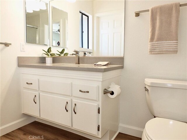 bathroom featuring wood-type flooring, toilet, and vanity