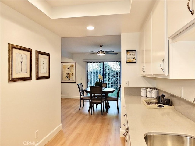 dining area featuring sink, ceiling fan, and light wood-type flooring