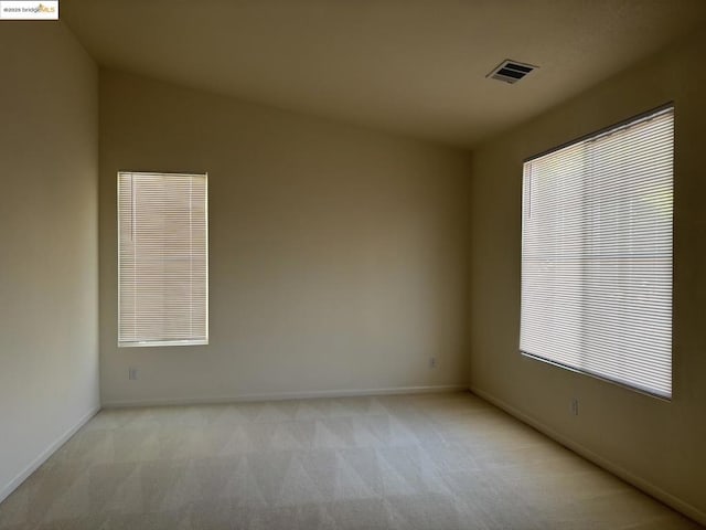 empty room featuring vaulted ceiling and light colored carpet