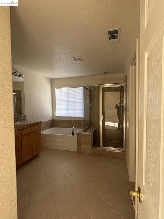 bathroom featuring vanity, plus walk in shower, tile patterned flooring, and a textured ceiling