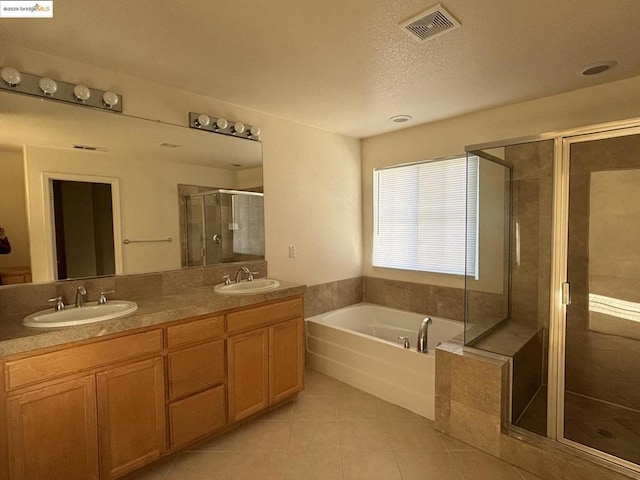 bathroom with vanity, independent shower and bath, tile patterned flooring, and a textured ceiling