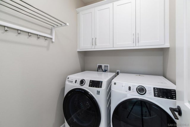 clothes washing area with cabinets and separate washer and dryer