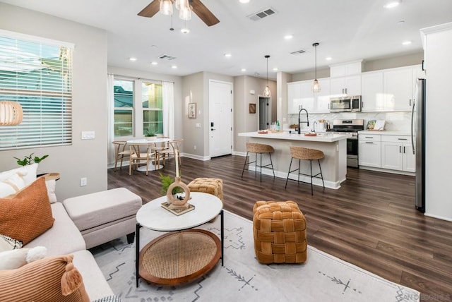 living room featuring sink, dark wood-type flooring, and ceiling fan