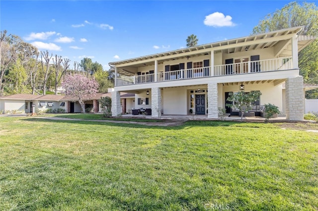 rear view of house featuring a patio area, a lawn, and a balcony