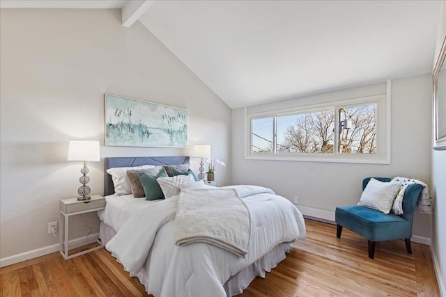 bedroom with lofted ceiling with beams and light hardwood / wood-style flooring