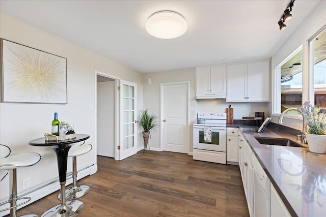 kitchen featuring white cabinetry, sink, dark hardwood / wood-style flooring, baseboard heating, and white appliances