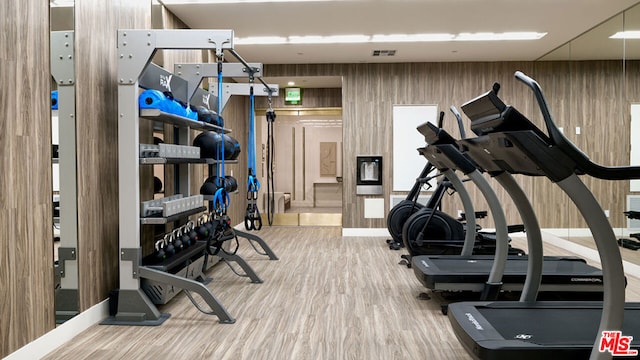 workout area with hardwood / wood-style floors and wooden walls