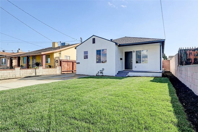 view of front of house with fence, a front lawn, and stucco siding