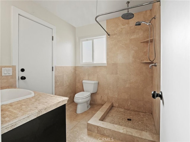 bathroom featuring tile patterned flooring, tile walls, tiled shower, vanity, and toilet