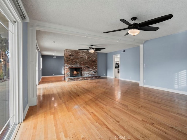 unfurnished living room featuring a fireplace, light hardwood / wood-style floors, and a textured ceiling