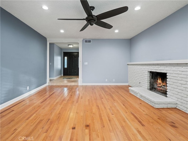 unfurnished living room featuring light hardwood / wood-style flooring, a fireplace, and ceiling fan